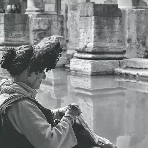 A lady sitting at the great Bath at the Roman Baths